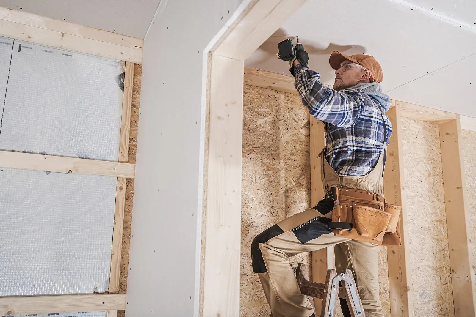 Vakman monteert gipsplaten op een metal stud wand in een kamer
