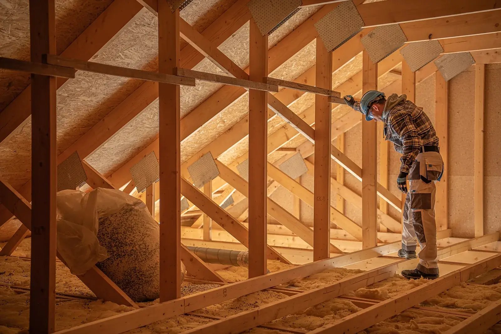 Bouwer werkt aan de houten kapconstructie van een zolder die binnen de bestaande kap wordt afgebouwd