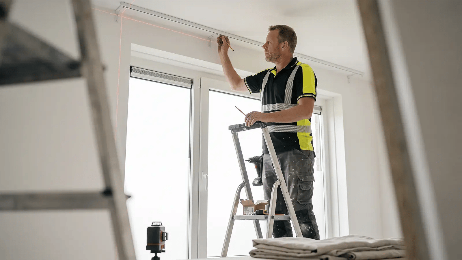 Klusjesman monteert een gordijnrail met een laserwaterpas in een woning in Groningen